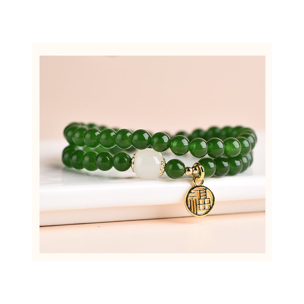 Green beaded bracelet with a gold charm on a beige background