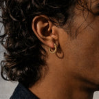 Homme aux cheveux bouclés portant des boucles d’oreilles en forme d’anneau Ouroboros
