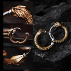 Une paire de boucles d’oreilles Ouroboros en forme d’anneau exposées sur des rochers sombres